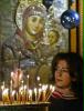 Woman lights candles at Bethlehems Church of Nativity